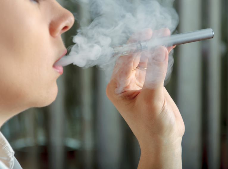 Close up of woman holding a electronic cigarette and exhaling smoke