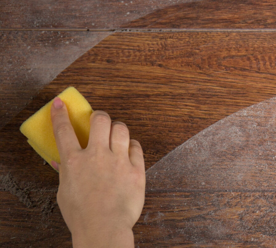 Person cleaning dust from a wooden surface