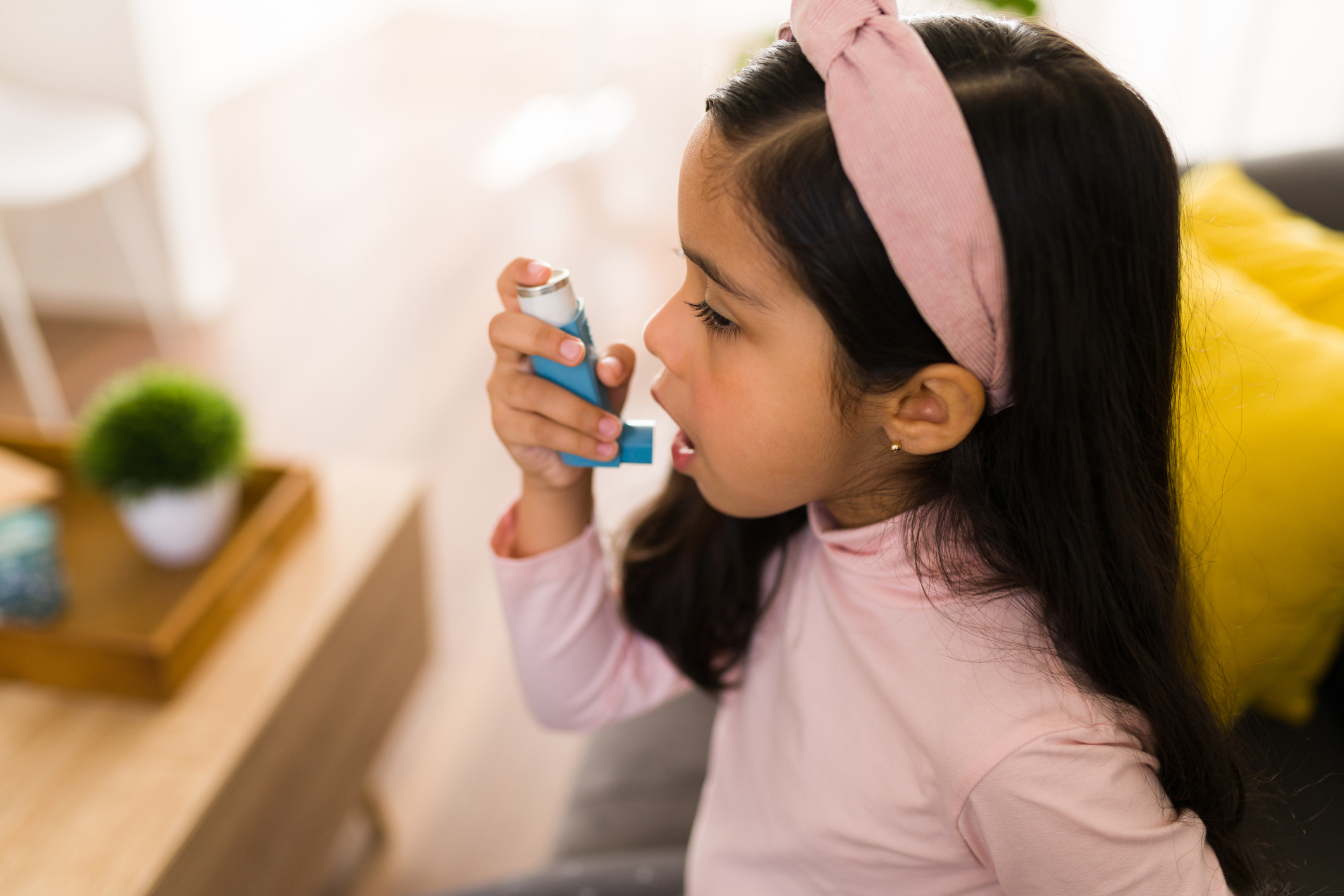 Side view of a little girl using an asthma inhaler