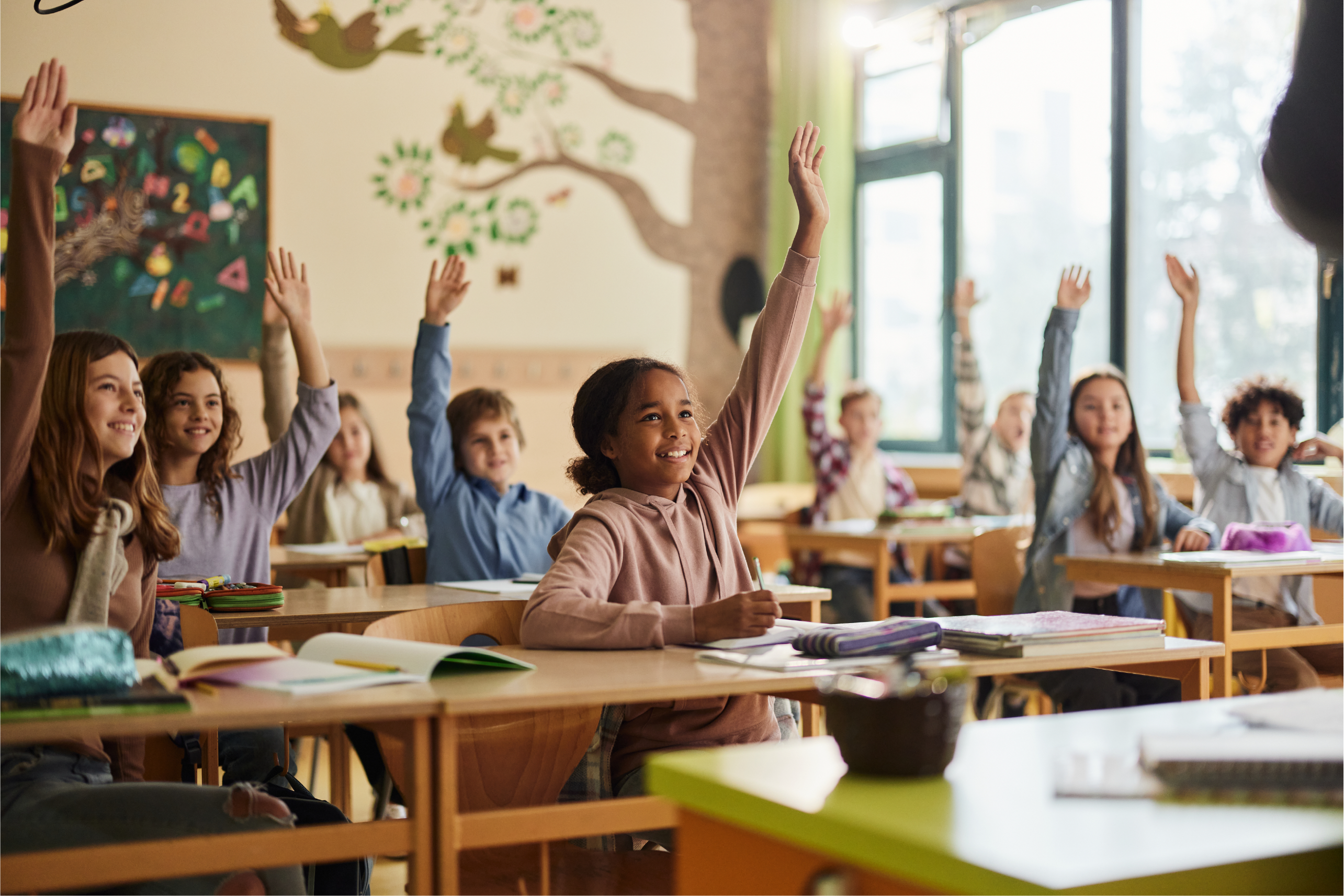 Children in a classroom with their hands raised.